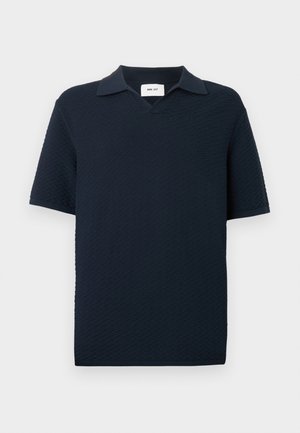 Sinine lühikeste varrukatega polo-särk, millel on tekstuuriga lainemuster ja väike avatud krae, esitletud valgel taustal.