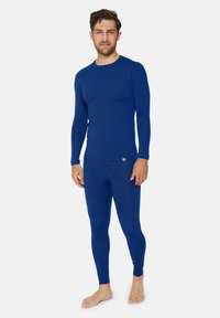 Maglietta termica blu a maniche lunghe e leggings abbinati, realizzati in un tessuto morbido con una vestibilità aderente, caratterizzati da cuciture minime e un piccolo dettaglio con logo.