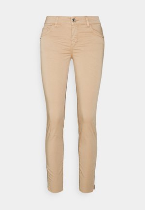 Beige pants valmistettu pehmeästä puuvillaseoksesta, joissa on kapea istuvuus, etutaskut ja vetoketjusomistus nilkoissa. Klassinen viiden taskun muotoilu.