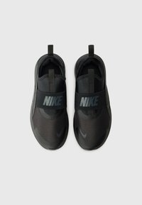 Black Nike slip-on shoes with mesh fabric, a thick elastic strap featuring the Nike logo, and a textured rubber sole.
