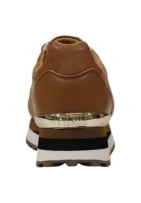 Sneaker marrone con tomaia in pelle testurizzata, suola intermedia bianca spessa e striscia nera di accento. Dettaglio metallico sul tallone con il nome del marchio.