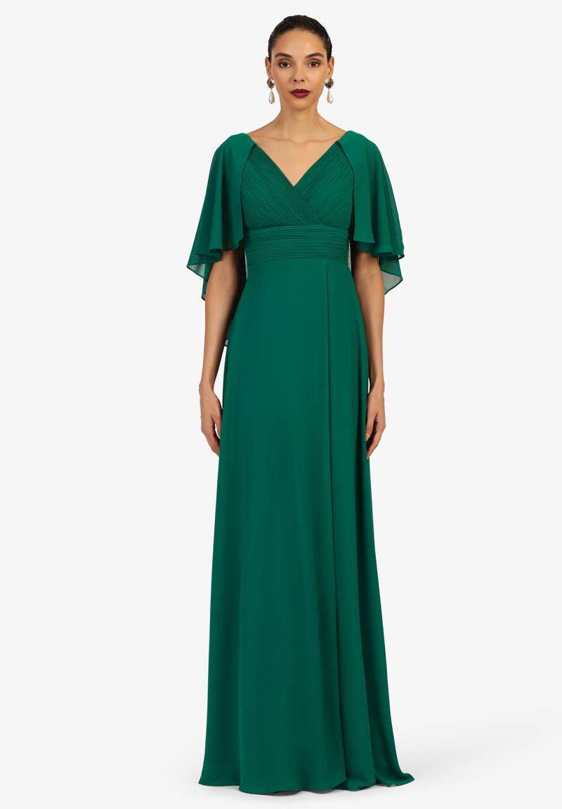 Grünes Abendkleid aus leichtem Stoff, mit V-Ausschnitt, schwingenden Ärmeln und gefälteltem Oberteil, das in einen bodenlangen Rock übergeht.