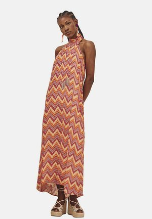 Vestido maxi con cuello halter. Presenta un patrón de zigzag en naranja, rojo y amarillo. Tejido fluido con un ligero brillo, abertura lateral para mayor movimiento.