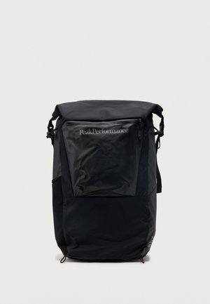 Black vertical backpack with front zip pocket and "Peak Performance" text, made of smooth water-resistant material.