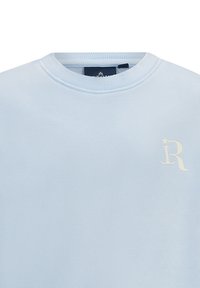 Felpa azzurra con scollo rotondo, realizzata in materiale morbido. Presenta un logo stilizzato bianco a forma di "R" sul petto e polsini a costine.