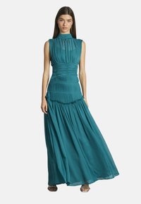 Türkisfarbenes Maxikleid mit gefaltetem Oberteil, hohem Kragen und fließendem Rock. Verfügt über geraffte Details und ein geschichtetes Design. Der Stoff wirkt leicht.