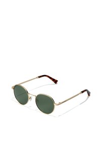 Gafas de sol redondas con lentes verdes, montura de metal dorado y puntas en patrón de carey en las varillas. Incluye almohadillas nasales ajustables.