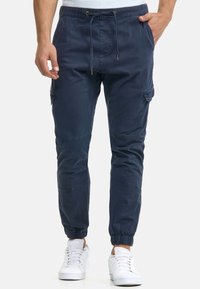 Mörkblå cargo joggers i bomull med dragsko i midjan, avsmalnande ben, sidofickor och elastiska muddar.