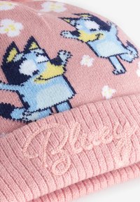 Berretto a maglia rosa con polsino a costine. Presenta cani da cartone animato e motivi floreali. Ricamo "Bluey" sul polsino. Texture morbida.