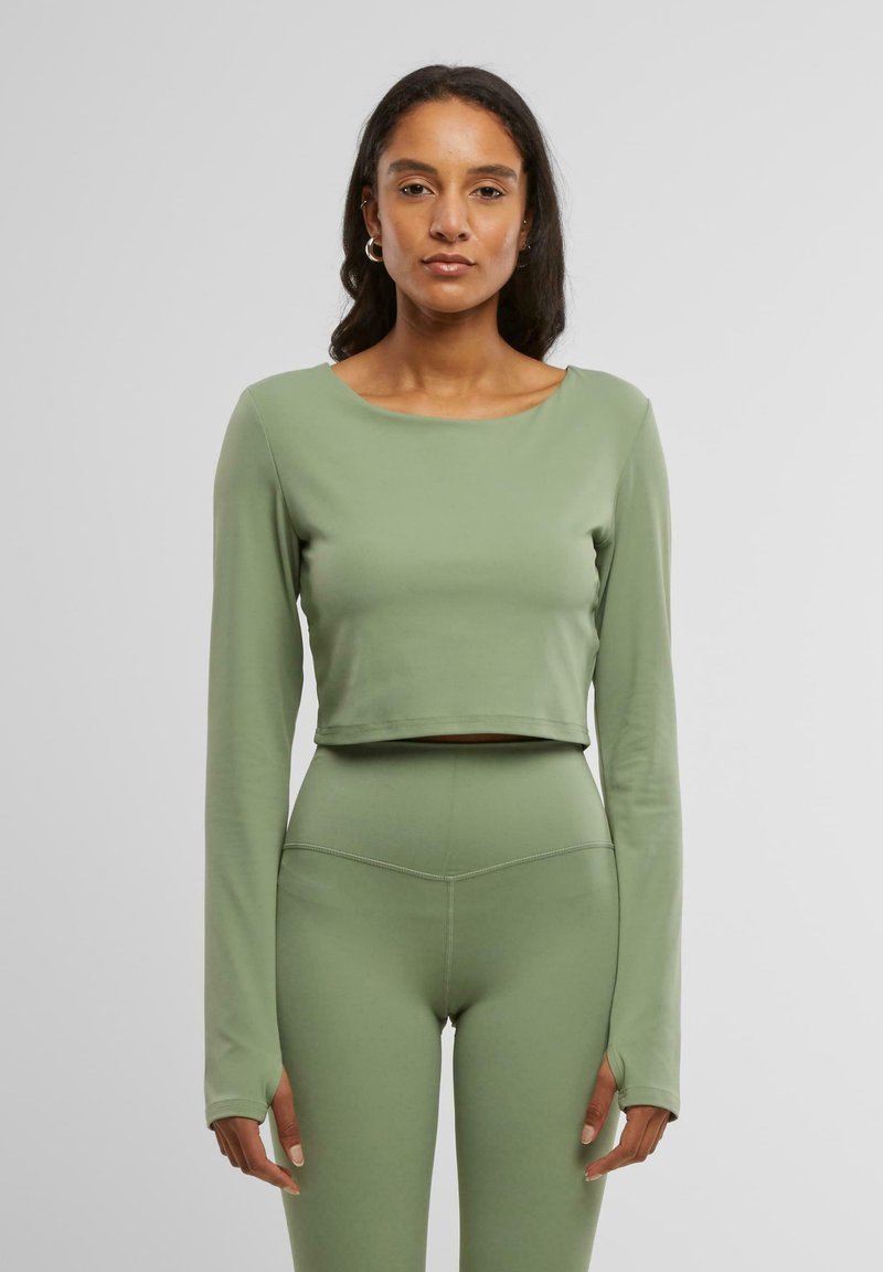 Zöld, cropped, hosszú ujjú felső sima, rugalmas anyagból; hozzá illő, magasító derekú leggings, varrási részletekkel.