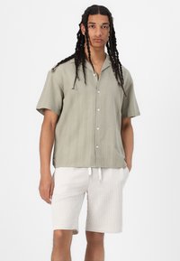 Short-sleeve, light green striped shirt with buttons, paired with beige and white striped shorts, featuring drawstring waist and cuffed hems.
