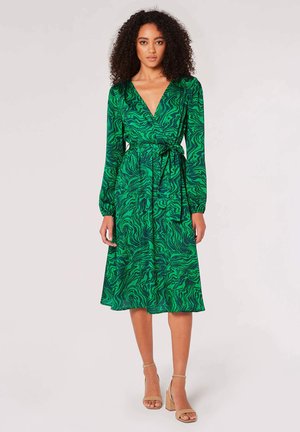 Robe portefeuille verte avec un motif tourbillonnant, des manches longues, une ceinture à la taille et une jupe fluide qui tombe sous le genou.