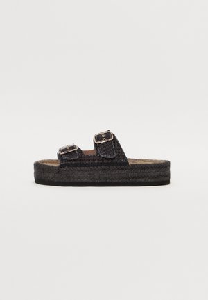 Black woven slide sandal with two buckled straps, textured upper, jute-like midsole, and flat rubber sole for comfort.