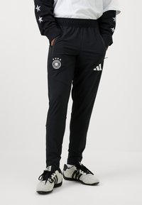 Schwarze Sporthosen mit elastischem Bund, Seitentaschen, Teamlogo mit fünf Sternen und weißem Adidas-Logo.