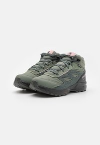 Zapatillas de senderismo verdes con parte superior de malla, suela de goma negra y acentos en rosa. Presentan un diseño de superposición y una puntera reforzada.