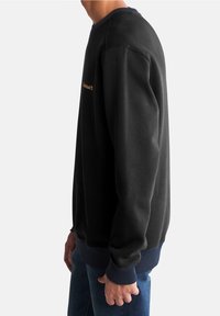 Felpa nera con polsini a coste di colore blu navy, colletto rotondo e logo dorato sul petto. Il materiale sembra morbido e leggermente texturizzato.