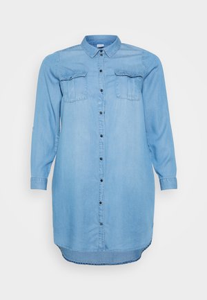 Šviesiai mėlyna džinsinė suknelė su mygtukų užsegimu priekyje, dviem krūtinės kišenėmis ir ilgomis rankovėmis su apykaklės detalėmis. Lygus paviršius ir iki kelių.