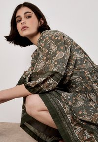 Vestido verde con estampado paisley y motivos florales. Tejido suave, corte relajado, mangas tres cuartos y un dobladillo detallado.