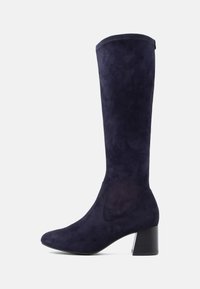 Térdmagasságú csizma sötét navy velúrból, hegyes orral és tömbsarkal. Simaság jellemzi, minimális varrási részletekkel.