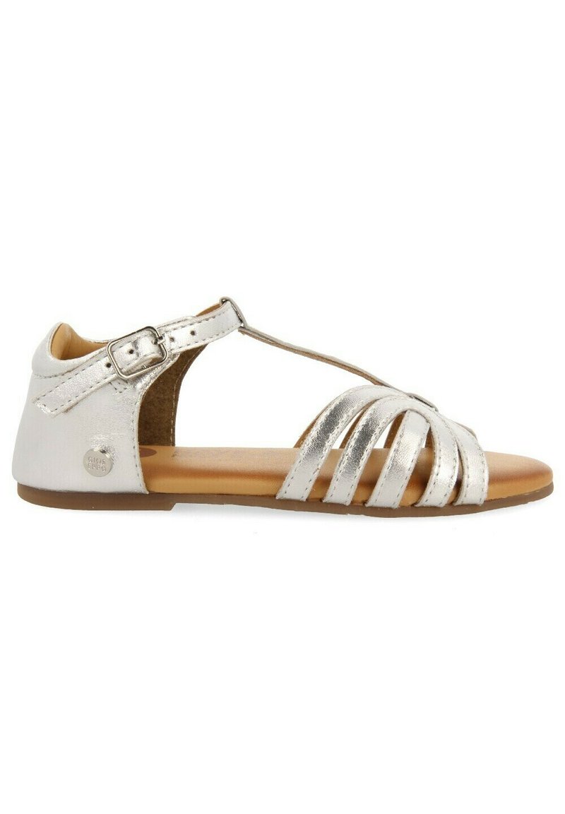 Sandal in argento metallico con cinturino alla caviglia regolabile, lato aperto, multiple cinghie frontali e suola leggera marrone.