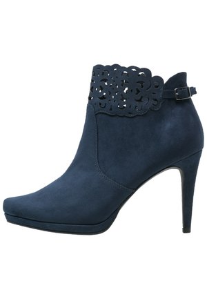 Bottine en daim bleu marine avec un design floral découpé au laser sur le haut, un bout effilé et un talon aiguille haut.
