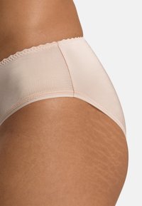 Panties beige chiaro realizzati in un tessuto liscio e elasticizzato, con una vita a scallop, bordi senza cuciture e un design aderente.