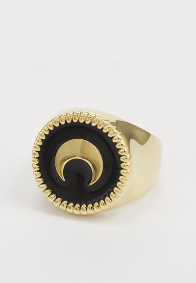 Anello dorato con una pietra circolare nera decorata da un design a forma di mezzaluna. I bordi texturizzati con piccole scanalature aggiungono dettagli.