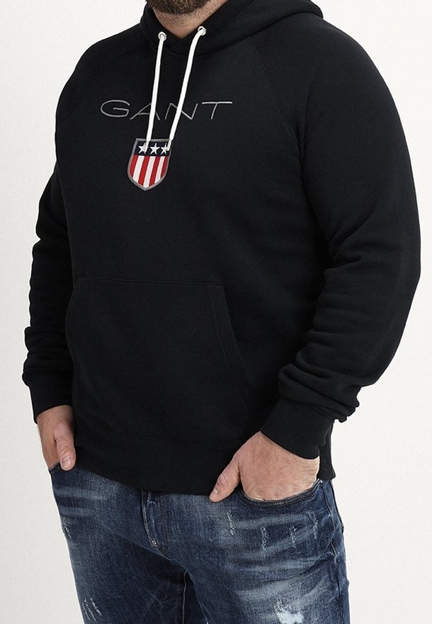 Zwarte hoodie van een katoenmix, met een logo en schildontwerp in rood en blauw, kangoeroezak en capuchon met trekkoord.