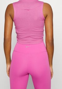 Crop top rosa a coste aderente con scollatura rotonda, abbinato a leggings rosa a vita alta con un piccolo logo sulla vita.