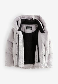 Leichte, graue Steppjacke mit schwarzem Innenfutter, Knopfleiste, elastischem Saum und Logetikett innen. Verfügt über eine abnehmbare Kapuze.