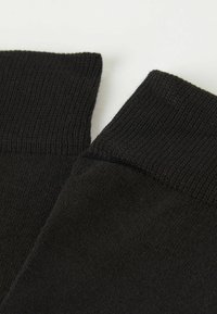 Sorte sokker med ribbede manchetter, der har en blød tekstur og sømløst design. Materialet ser strækbart og tætsiddende ud.