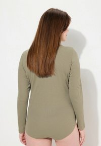 Body lungo verde oliva in tessuto texture, con scollatura rotonda e orlo curvato. La vista posteriore mostra una vestibilità liscia e minimalismo nei dettagli.