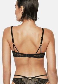 Zwarte kanten beha met verfijnde bloemmotieven, verstelbare bandjes en een haak- en oogsluiting aan de achterkant. Textuurrand details zichtbaar.