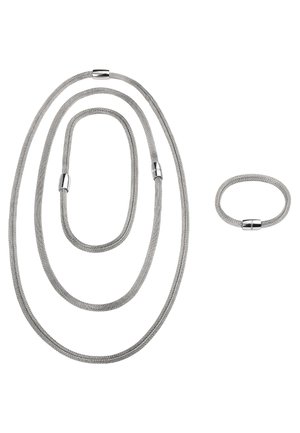 Conjunto de joyería de malla plateada que incluye tres cadenas flexibles de diferentes longitudes y un anillo a juego, todos con acentos metálicos lisos y cilíndricos.