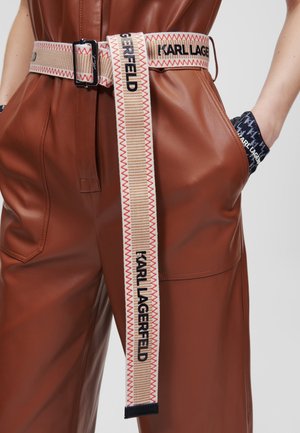 Brown leather pants with large front pockets and a beige fabric belt featuring red stitching and "KARL LAGERFELD" text.
