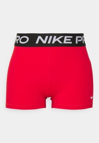 Shorts de sport rouges en tissu extensible. Présentent une taille noire NIKE PRO avec des lettres blanches et un petit logo blanc sur le côté.