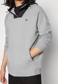 Felpa con cappuccio grigia in tessuto morbido, con colletto zip nero, dotata di tasca a marsupio e logo sul petto.