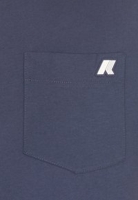 T-shirt blu navy con tessuto testurizzato, taschino con cuciture bianche a contrasto e un piccolo logo bianco sulla tasca.