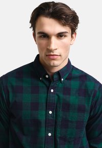 Groene en marineblauwe geruite button-up shirt met een zak, met een zachte textuur en klassieke kraag. Witte knopen accentueren de voorkant.