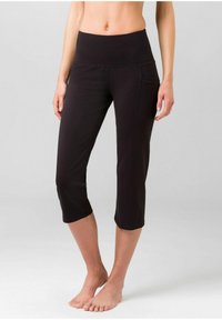 Schwarze Capri-Leggings aus dehnbarem Material, mit einem breiten Bündchen und einer Seitentasche für zusätzlichen Komfort. Glatte Textur und figurbetontes Design.