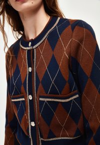 Brauner und marineblauer Argyle-Strickcardigan mit rundem Kragen, metallischen Knopfverschlüssen und zwei Taschen mit kontrastierender Bordüre.