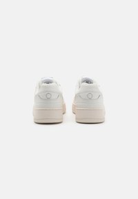 Hvide sneakers med en glat læderoverdel, der har en lys beige gummisål og diskrete blå syninger. Rund form med polstret krave.
