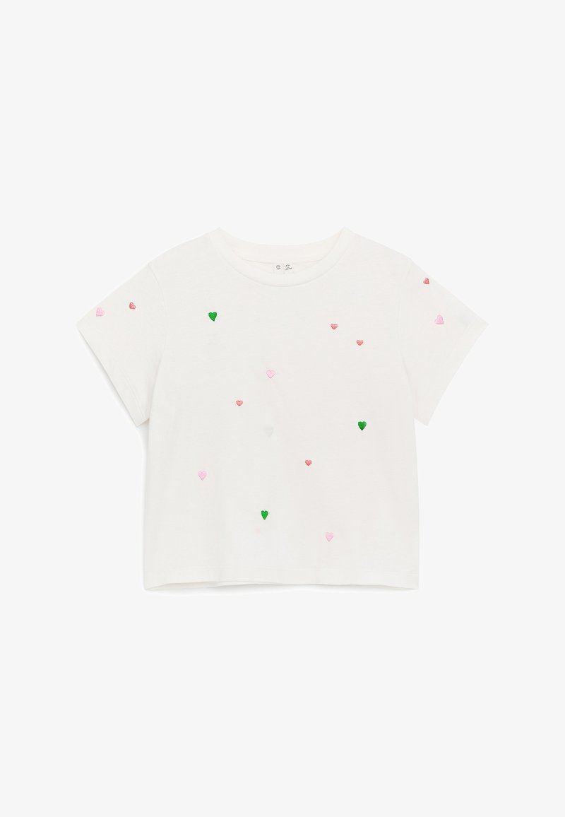 Crop top blanc à manches courtes avec de petits cœurs brodés verts, roses et rouges dispersés sur le devant et les manches.