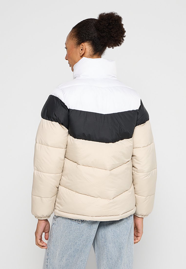 Chaqueta acolchada con un alto cuello, que presenta un diseño en bloques de color negro, blanco y beige, textura acolchada y puños elásticos.