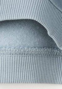 Pull bleu clair avec un ourlet côtelé et une doublure en polaire douce, orné de surpiqûres décoratives le long du bord et d'une texture lisse.