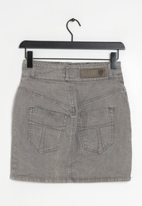 Falda de mezclilla gris en un perchero con una cinturilla rectangular, dos bolsillos traseros y costuras en contraste. Textura suave con un aspecto desgastado.
