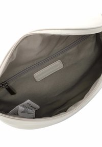 Inneres einer weißen Stofftasche mit glatter Textur, einem grauen Futter, einer Reißverschlusstasche und einem Markenetikett an der Seite. Pflegeetiketten sichtbar.