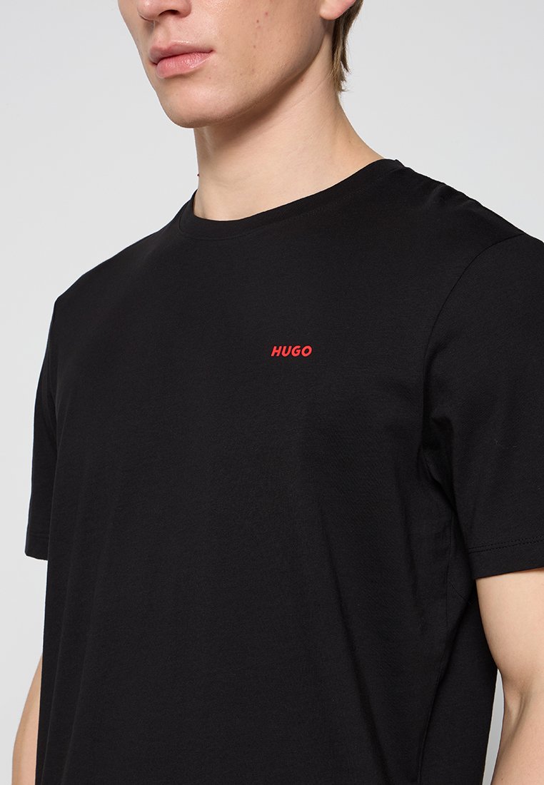 Czarny bawełniany t-shirt z okrągłym dekoltem i krótkimi rękawami. Logo "HUGO" w kolorze czerwonym na lewej piersi. Gładka faktura.