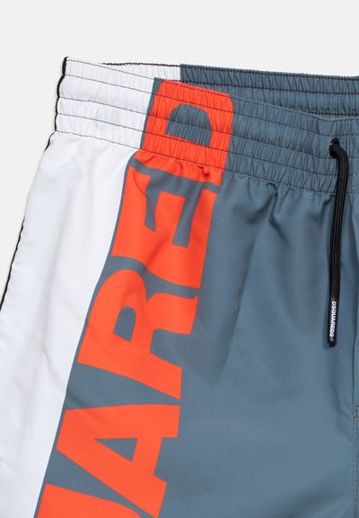 Διχρωματικό μαγιό με ελαστική μέση, μαύρο κορδόνι και μεγάλο έντονο πορτοκαλί κείμενο σε γκρι πλαϊνή λωρίδα. Άσπρο ύφασμα στην αριστερή πλευρά.