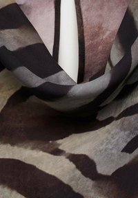 Silk scarf featuring an abstract design in shades of gray, black, and beige, with flowing, soft texture and irregular patterns.